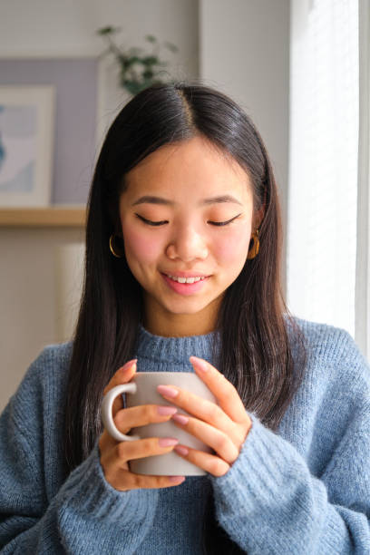 istock Asian woman is holding a mug and smiling. 2148192113