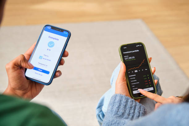 istock Two people are using their phones, one is paying a friend, other is investing. 2148192607