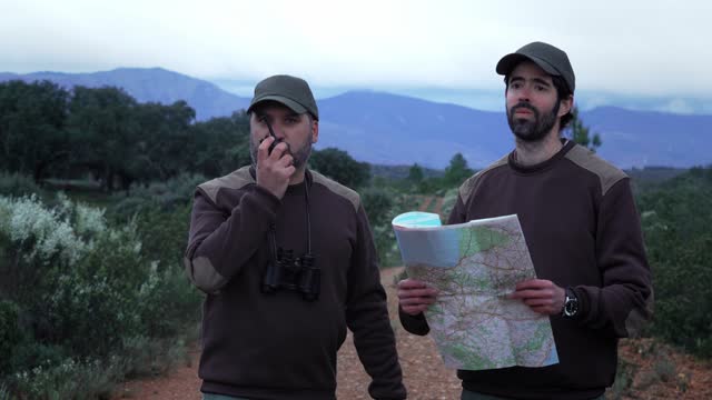 Forester Rural Ranger talking on walkie talkie radio checking road map at night - Environmental Wildlife Conservation Job