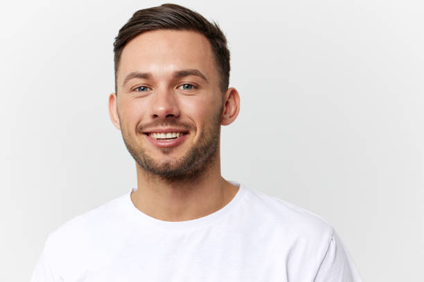 istock Joyful cute happy young tanned handsome man in basic t-shirt laugh at camera posing isolated on over white studio background. Copy space Banner Mockup. People emotions Lifestyle concept. Portrait 2148194465