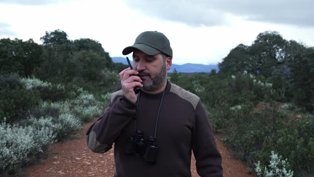 Man talking with walkie talkie radio walking on the National park Reserve - Forest Ranger