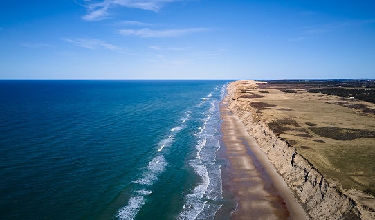 Drone shot of majestic mountain and beautiful seascape with waves and horizon against blue sky at Jutland, Denmark in summer