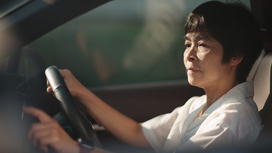 Asian mature woman touching screen to check the map gps or control the music radio while travel by car.