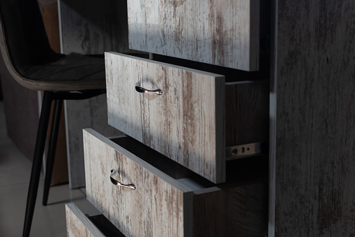Cabinet furniture. Opened extended drawers of office desk close-up made of original loft wood