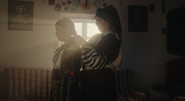 Mother Dressing Daughter in Ukrainian Folk Attire at Home