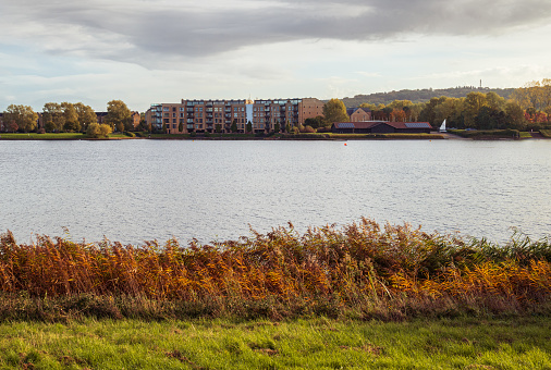 Autumn Lakeside view with residential area on opposite bank at Caldecotte lake