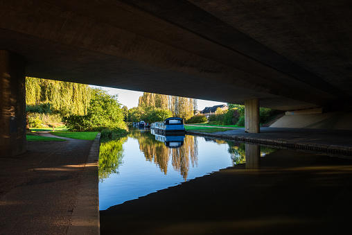 Grand Union Canal under the bridge of dural carriageway on sunny day in Milton Keynes