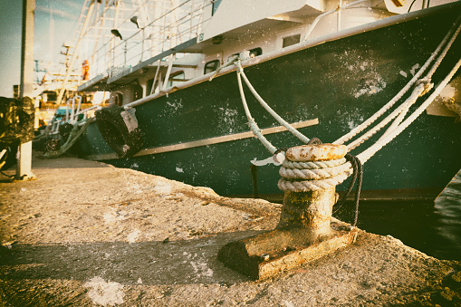 Vintage boat anchored in the harbor with visual aging effect on postcard