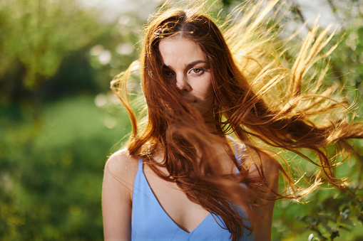 Portrait of a woman with long flyaway hair red hair in summer, the concept of health and care for long thick hair beauty. High quality photo