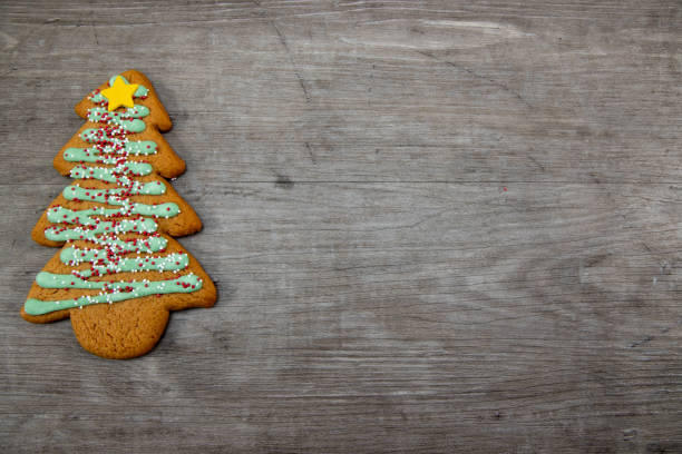 A delicious Christmas tree ginger bread with green icing, sprinkles and a yellow star on a wooden background