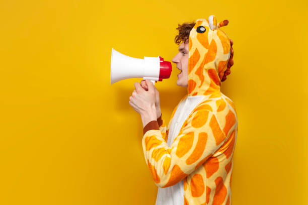 istock young joyful guy in funny children's giraffe pajamas speaks into megaphone and points his hand to the side 2148200940