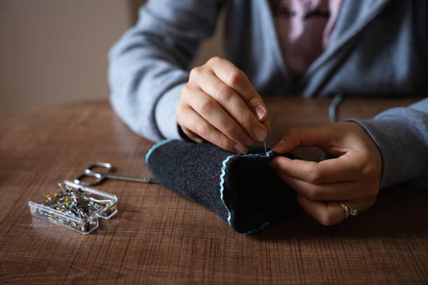 A young woman is hand sewing, detail image