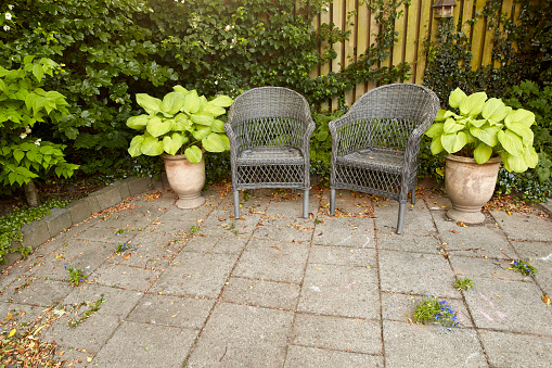 Rocking chairs sits on a brick patio with white columns.