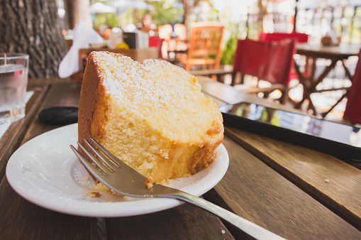 close up of delicious sponge cake served on a plate, with a fork, on a table outside the restaurant on a beautiful sunny day.