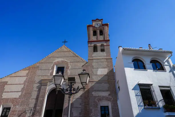 Restored facade of the Church of San Antonio de Padua with is bell tower in the middle of the hillside village of Frigiliana Spain