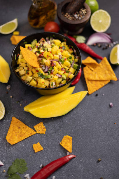 istock Freshly made mango salsa in a black ceramic bowl, nacho chips and ingredients 2148210004