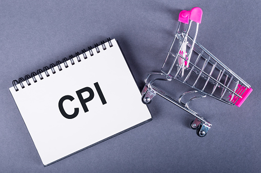 Text CPI - Consumer Price Index on a notepad next to a shopping trolley on dark gray background.