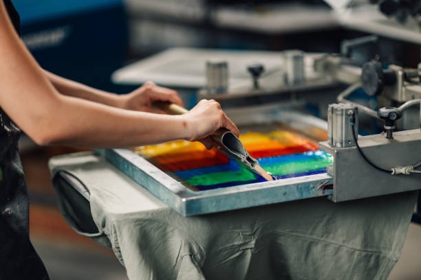 istock Close up of unrecognizable worker's hands screen printing with squeegee 2148210284