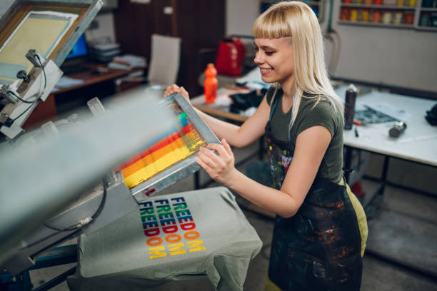 istock Happy graphic worker is screen printing on manual printing press. 2148210287