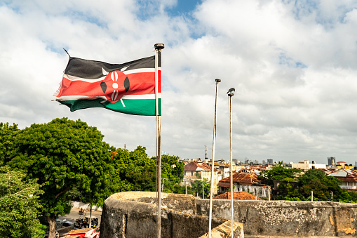 Kenya flag waving in the wind against the background of a blue cloudy sky.