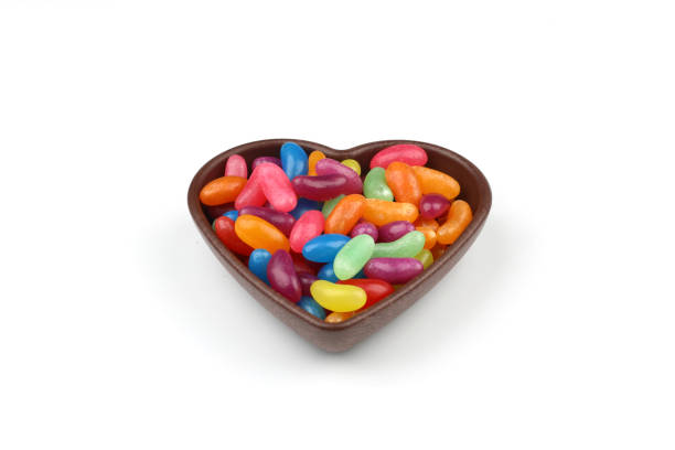 istock multi-colored sweet candies in heart shaped bowl on white background, top view. Space for text 2148211431