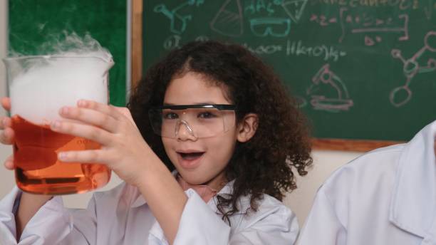 A science teacher with her class of elementary or middle school students showing off their class projects, homemade science models.