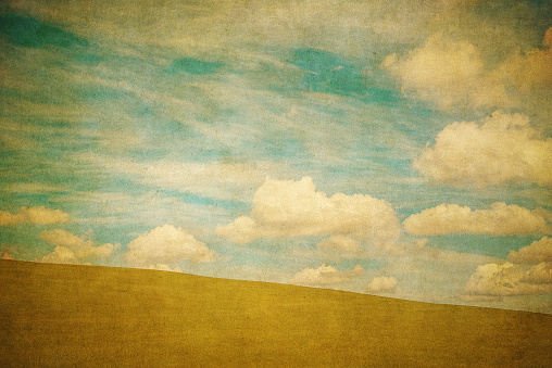 Vintage background of green field and blue cloudy sky