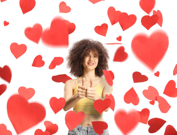istock Cheerful young female gesturing thumbs up under red hearts 2148214615