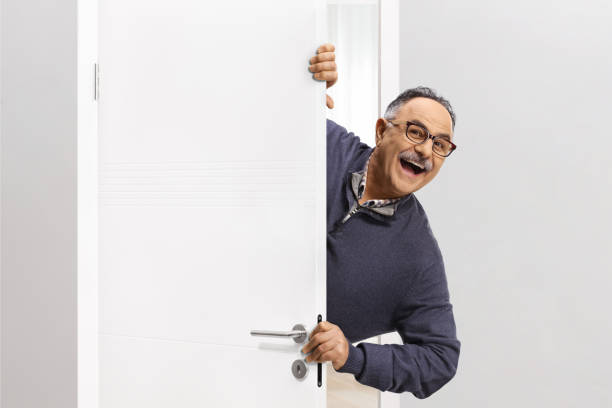 istock Cheerful mature man hiding behind a door 2148214784