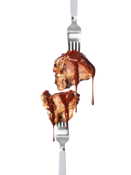 Grilled beef steaks poured with sauce on forks isolated on white background