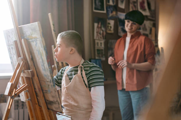 istock Boy with Down Syndrome Painting on Easel in Sunlight 2148215064