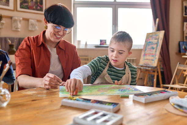 istock Boy with Down Syndrome Enjoying Art Class with Teacher 2148215086