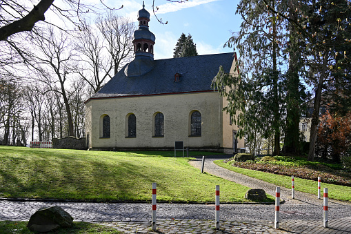 Frog's perspective of the front of the Catholic Court Church of St. Leodegar in Lucerne with its two towers and a clock with dial in sunshine and cloudless sky