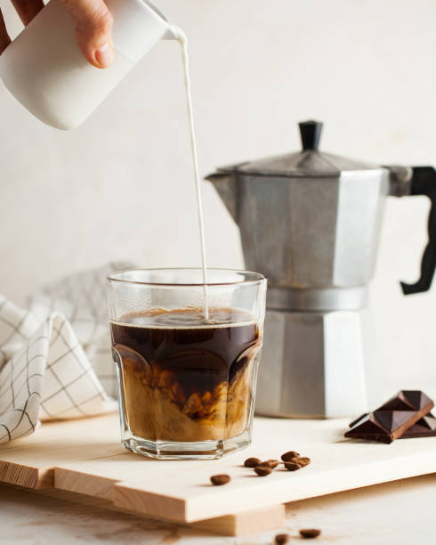 Cream swirls into coffee, blending with rich aromas