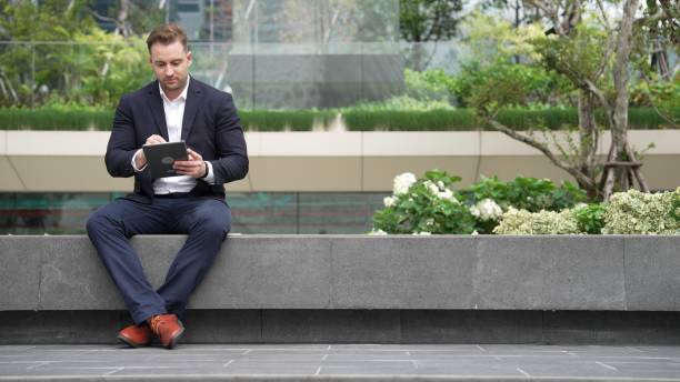 istock Smart businessman sitting while writing on tablet and planning strategy. Urbane 2148216589