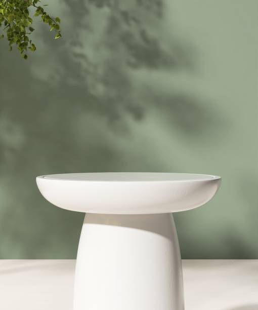 istock Empty white round stone table podium in dappled sunlight, leaf foliage shadow on green concrete wall 2148218454