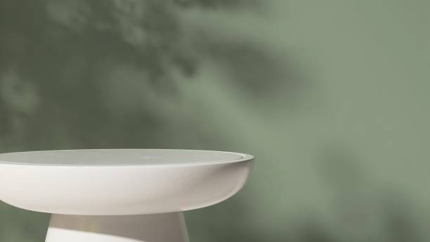 istock Empty white round stone table podium in dappled sunlight, leaf foliage shadow on green concrete wall 2148218455