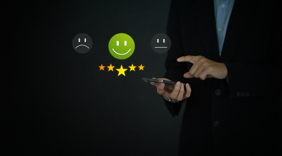 Businessman hand in black suit pointing at smartphone, show a five star rating.