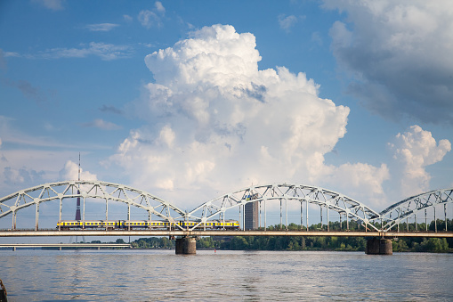 Panorama of the Daugava river in Riga, latvia, with a train from Latvian railways over dzelzcela tilts or Riga Railway Bridge with a skyline of business skyscrapers in background with high rise towers.