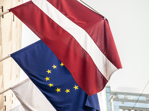 Picture of the flag of Latvia and the flag of the EU together in front of a building of Riga. Latvia is one of the main members of the European union since it joined the community in 2004.