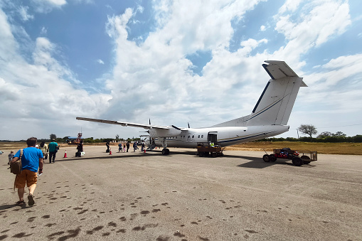 man passenger travelling with backpack, boarding small airplane, people climbing ramp on background, rear view