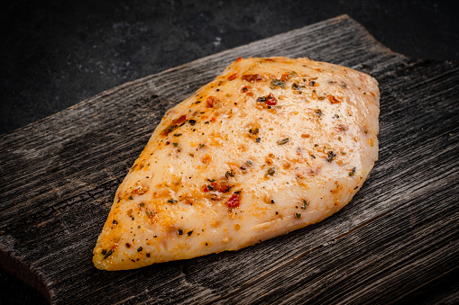 Sous vide chicken breast prepared for grilling with seasonings on wood