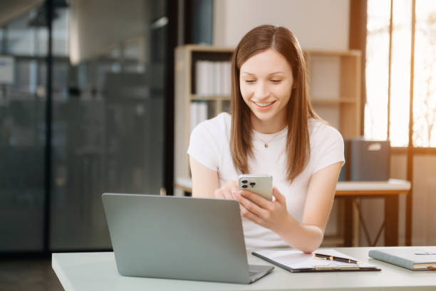 istock Beautiful woman using laptop and tablet while sitting at her working place. Concentrated 2148223050