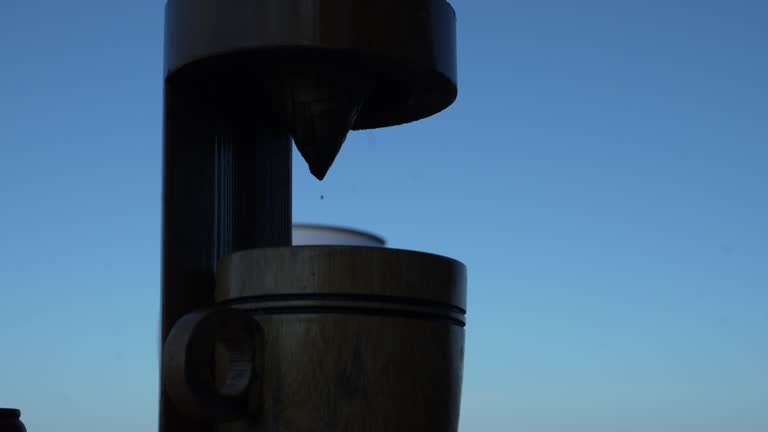 Coffee drips slowly in a wooden cup from a manual coffee grinder in the morning at camping