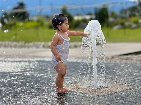 1-year-old child cooling off in the cold waters of a public park in the summer