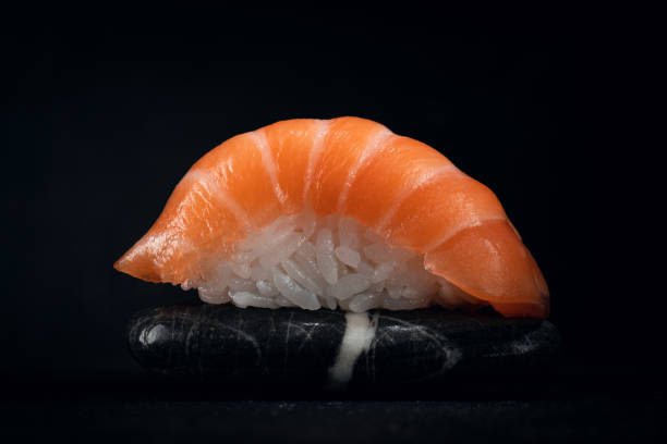 istock One sushi salmon on a rock in the dark, close up 2148224355