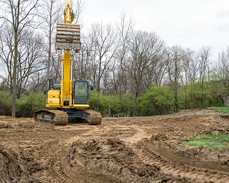Excavator or backhoe bucket lowering to scoop dirt at construction site.