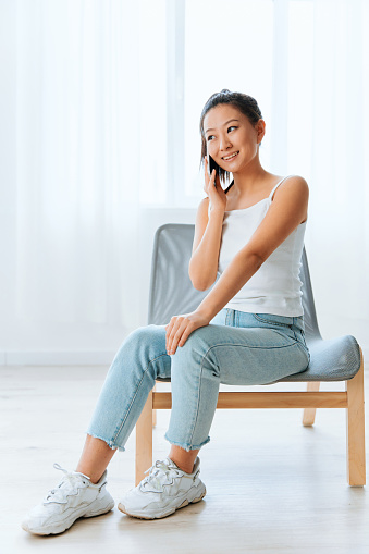 Cheerful smiling tanned lovely young Asian woman accepts congratulations from friends in call using phone at home living room. Distance communication Social media concept. Cool offer Banner Wide angle