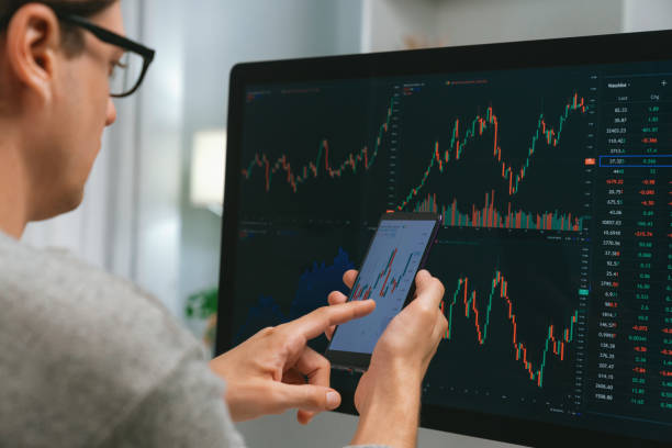istock Investors pointing on screen with smartphone with laptop in stock. Pecuniary. 2148227379