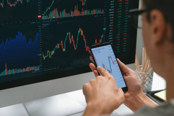 istock Investors pointing on screen with smartphone with laptop in stock. Pecuniary. 2148227633